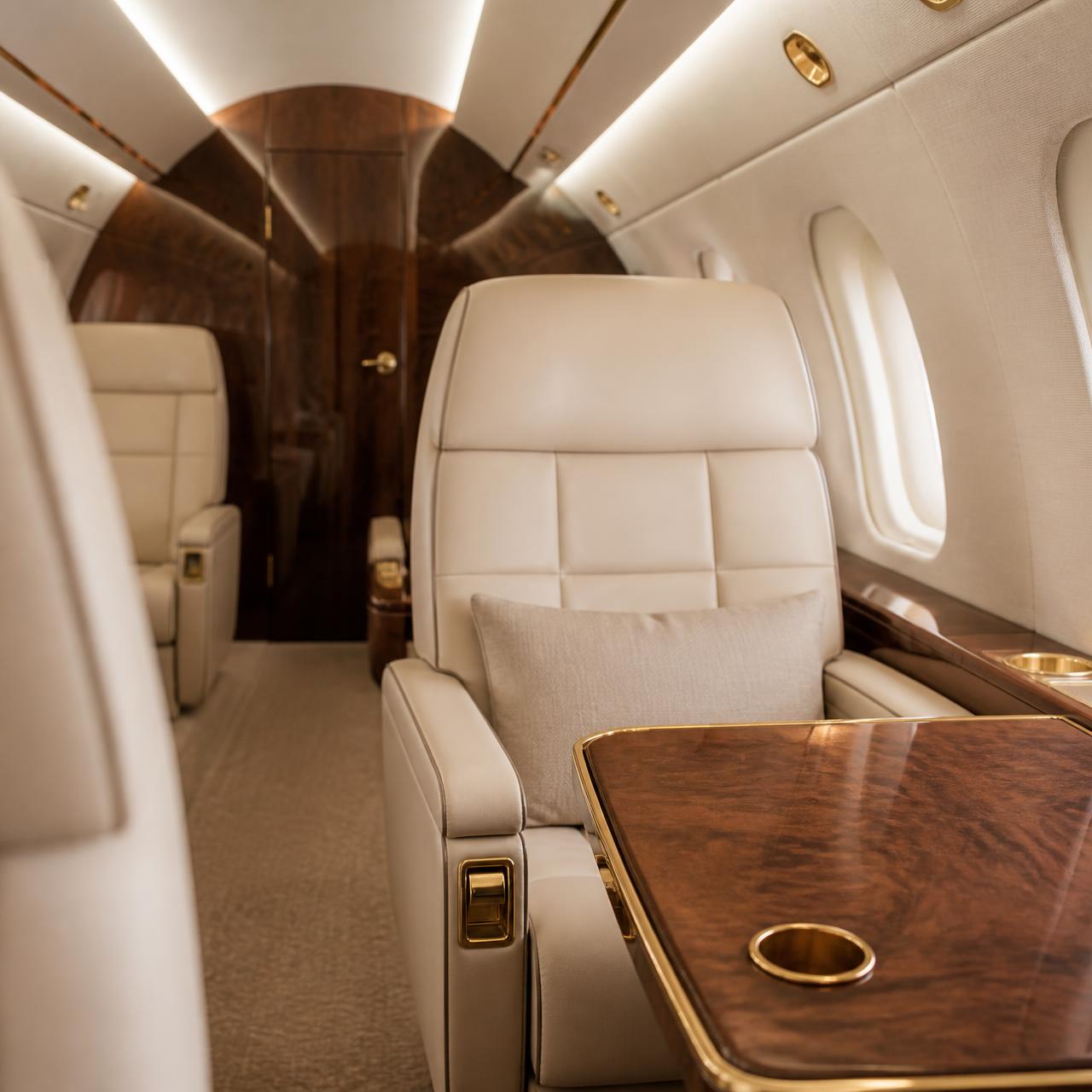Cream leather seating and polished wood tables inside an executive aircraft cabin